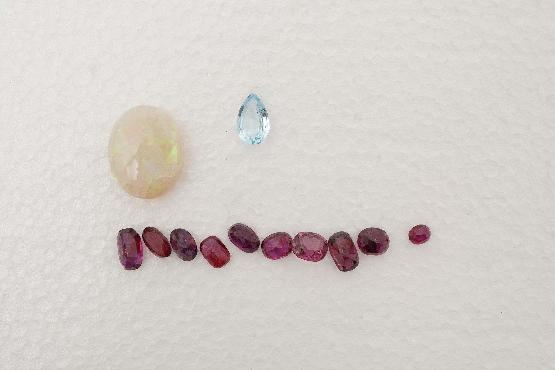 A collection of loose rubies, aquamarines and opals